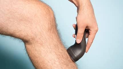 Caucasian man shaving hair from legs