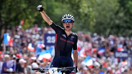 Thomas Pidcock of Team Great Britain celebrates at finish line as gold medal winner during the Men's Cross-Country on day three of the Olympic Games Paris 2024 at Elancourt Hill on July 29, 2024 in Elancourt, France. (Photo by Alex Broadway/Getty Images)