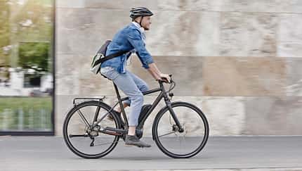Mann pendelt mit seinem E-Bike zur Arbeit