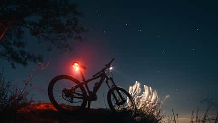 Silhouette of mountain bicycle with glowing lamps