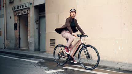 Frau fährt mit stylishem City-E-Bike von Riese und Müller durch die Stadt. E-Bike-Trends 2025.