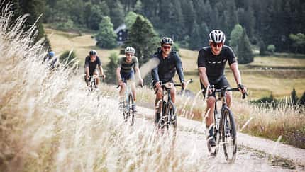 Gravelbikes,Action,vier Fahrer hintereinander,Grasbüschel