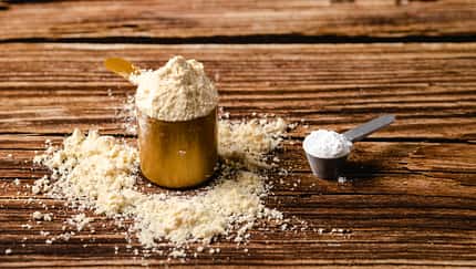 Sports supplements on a wood table background Vertical composition with protein and creatine