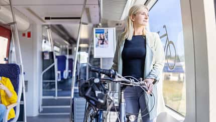 Frau steht mit ihrem Fahrrad in einem Zug 