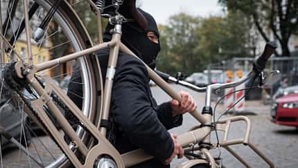 Ein maskierter Mann trägt ein Fahrrad.  