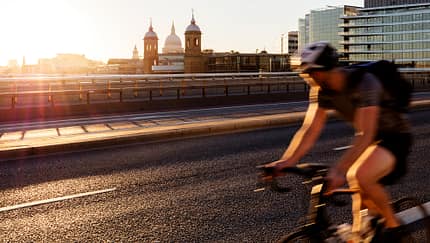 London, verschwommene Bewegung eines schnell fahrenden Radfahrers auf der London Bridge mit Blick auf die St. Paul's Cathedral im Hintergrund