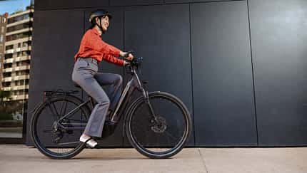 Eine Frau pendelt bequem mit einem Elektrofahrrad, gekleidet in Freizeitkleidung mit Sicherheitsausrüstung. Eine Frau pendelt bequem mit einem Elektrofahrrad, gekleidet in Freizeitkleidung mit Sicherheitsausrüstung.