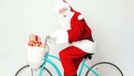 Surprised Santa Claus riding a bike with presents Surprised Santa Claus riding a bike with presents