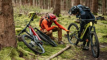Zwei Mountainbiker besprechen etwas auf einem Trail, zwei Mountainbikes