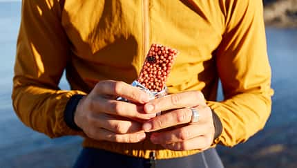 Hands of cyclist holding energy bar on sunny day Hands of cyclist holding energy bar on sunny day