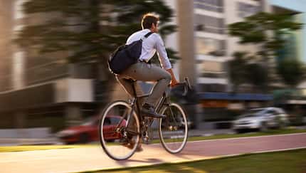 Verschwommener Fahrradfahrer mit Umhängetasche in der Stadt Verschwommener Fahrradfahrer mit Umhängetasche in der Stadt