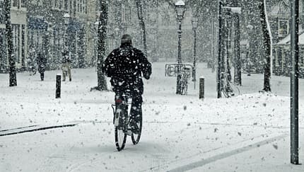 Ein Biker wagt es, mit dem Fahrrad auf dem frischen Schnee zu fahren.
