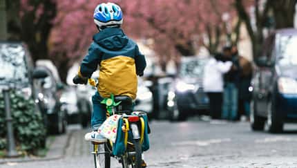 Ein kleiner Junge radelt in einer Straße.
