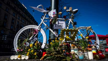 Weißes Ghost Bike mit Kerzen und Blumen 