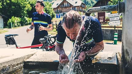 Ein Fahrradfahrer kühlt sich bei Hitze mit Wasser ab. Ein Fahrradfahrer kühlt sich bei Hitze mit Wasser ab.