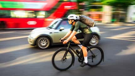 Verschwommene Bewegung eines Mannes, der auf einer stark befahrenen Straße im Zentrum von London, Großbritannien.