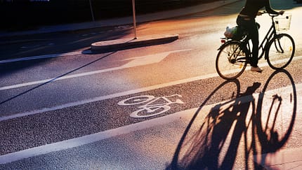 Radweg am Abend. Schild für Fahrrad auf den Asphalt gemalt. Auto und Verkehr im Hintergrund. Radweg am Abend. Schild für Fahrrad auf den Asphalt gemalt. Auto und Verkehr im Hintergrund.