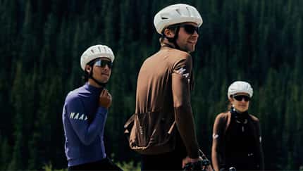 Drei Radfahrer in MAAP Apex Aeon Radkleidung vor einem Wald.