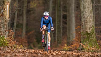 Athlete gravel cycling through autumn forest in Baden-Wuerttemberg