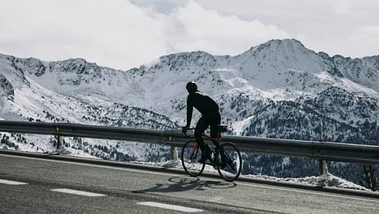 Andorra, cyclist on mountain road with snowy mountains in the background