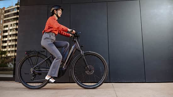 Eine Frau pendelt bequem mit einem Elektrofahrrad, gekleidet in Freizeitkleidung mit Sicherheitsausrüstung. 
