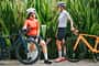 2 Asian chinese woman road bike cyclist side by side at public park in the morning resting talking