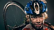 Mud splattered cyclist carrying bicycle