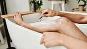 Man shaving his leg in bathroom