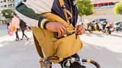 Casual businessman with bicycle taking cell phone out of backpack in the city, Barcelona, Spain