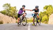 Male athletes doing fist bump while sitting on bicycles