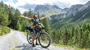Man bikepacking, he stops and embraces nature arms wide open