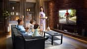 Family with children cheering and watching Cycle race on TV