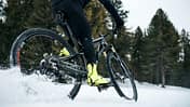 Midsection of mountain biker riding in snow outdoors in winter.