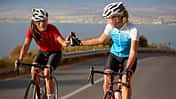 Cyclist passing water bottle to training partner