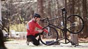Side view of athlete adjusting bicycle on road during sunny day