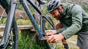 Man fixing mountain bike on trail