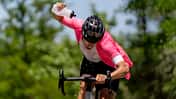 Athlete riding bicycle pouring water from bottle on sunny day