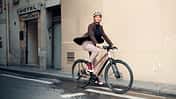 Frau fährt mit stylishem City-E-Bike von Riese und Müller durch die Stadt. E-Bike-Trends 2025.