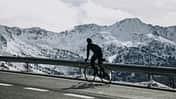 Andorra, cyclist on mountain road with snowy mountains in the background