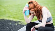 Young woman with long red hair wearing sportswear, exercising outdoors.