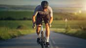 Professional cyclist sprinting on the road at sunset.