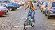 Olaf Schubert fährt ein Retro-Fahrrad auf einem Parkplatz