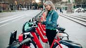 Reife Frau im Urlaub und Mieten eines E-Bikes, um Barcelona zu erkunden.