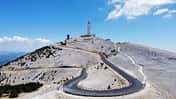 Schmale Autobahn, die zum Mont Ventoux in Frankreich führt, mit blauem Himmel im Hintergrund.