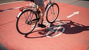 Schatten eines unkenntlichen Radfahrers, der mit dem Fahrrad auf dem Radweg fährt.