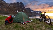 Solo woman bikepacking on a remote beach at sunset, Norway