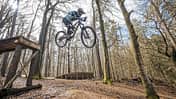 Mountainbiker springt mit einem MTB über einen Holzsprung im Wald, aufgenommen in Beerfelden.