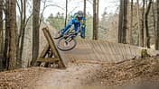 Mountainbiker auf einem Trail im Bikepark Beerfelden, fährt auf einer Holzkurve (Wallride) durch den Wald.