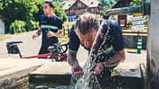 Ein Fahrradfahrer kühlt sich bei Hitze mit Wasser ab. 