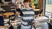 Mann, der sich im Café um sein Elektrobike kümmert und mit seinem Tablet nach etwas sucht.
